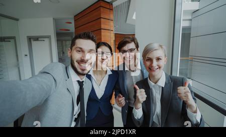 POV of Happy business team having online video chat using smartphone camera and talking to their colleague in modern office indoors Stock Photo