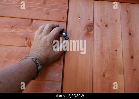 POV hand opening or closing a new wooden shed door Stock Photo