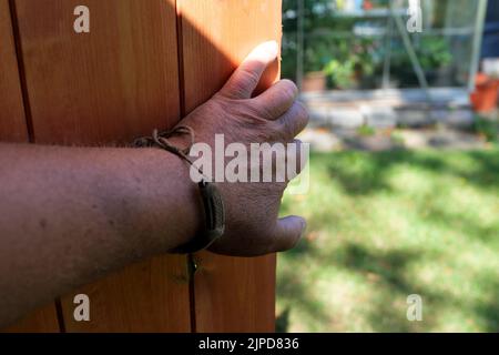 POV hand opening or closing a new wooden shed door Stock Photo