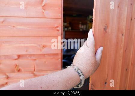 POV hand opening or closing a new wooden shed door Stock Photo