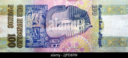 Large fragment of reverse side of an old 100 LE EGP one hundred Egyptian cash money banknote Tutankhamen's mask above frieze at centre of vertical for Stock Photo