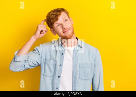 Photo portrait of nice young man scratch hand look confused empty space dressed trendy denim garment isolated on yellow color background Stock Photo