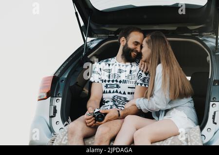 Middle-aged couple sitting in the trunk of car and smiling, caucasian man and woman enjoying road trip Stock Photo