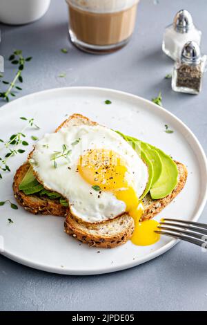 Avocado toast on a toasted multigrain bread with a fried egg Stock Photo