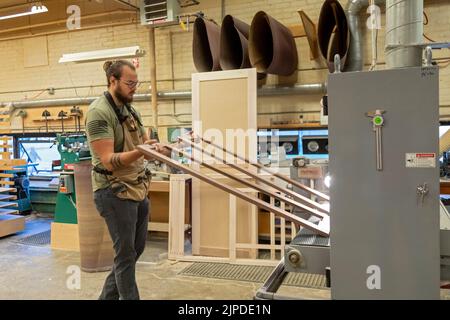 Kalamazoo, Michigan - Skilled workers build custom cabinets at the Homestead Cabinetmakers shop, located in the Park Trades Center. This machine light Stock Photo