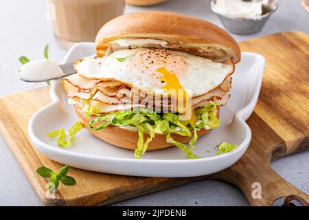Turkey bagel breakfast sandwich with lettuce and fried egg Stock Photo