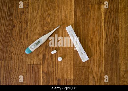 positive corona swipe test showing two bars for Covid 19 infection along with medication and clinical thermometer Stock Photo