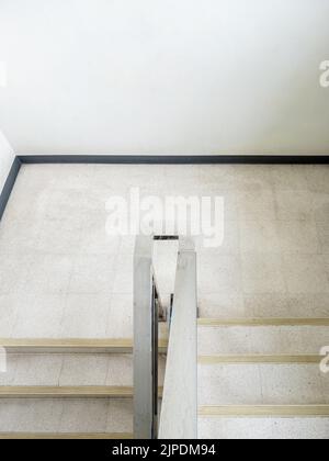 The empty dog-leg staircase with the metal handrail in the office building, above view with the copy space. Stock Photo