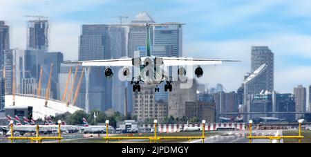 Close up back view of four engine passenger aircraft landing at London City Airport Newham with O2 & arena Canary Wharf in London Docklands England UK Stock Photo