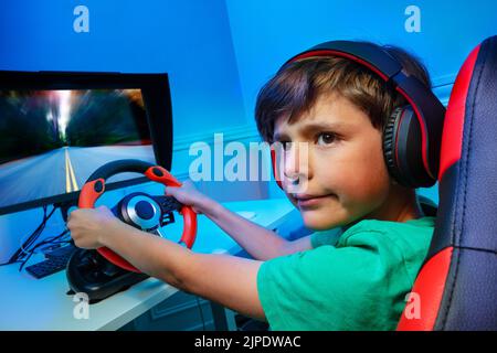 Boy with steering wheel play race game turn and look back Stock Photo
