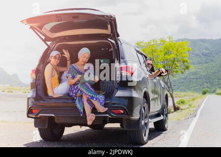 Three best friends enjoying traveling in the car on a road trip. Stock Photo