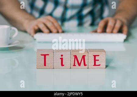 The inscription Time on wooden blocks, Background, Man typing on the keyboard, a cup of coffee, creative concept, Completion time, due date Stock Photo