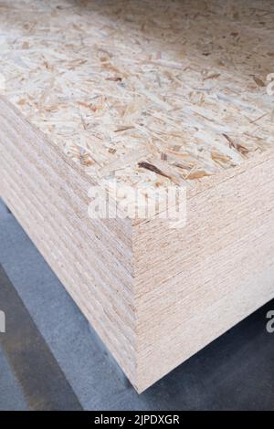 The stack of OSB sheets are stacked in a hardware store on a pallet. plywood with fragments of compressed sawdust, prepared for construction. Selectiv Stock Photo