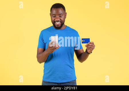Black Male Using Phone And Credit Card Making Payment, Studio Stock Photo