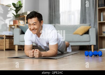 Motivated asian man having workout at home Stock Photo
