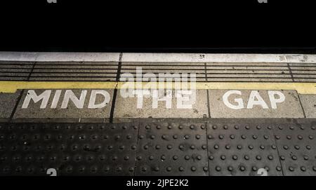 A 'Mind The Gap' notice painted on the platform of a London Underground tube station. Stock Photo