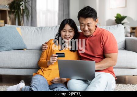 Relaxed japanese spouses using notebook and credit card Stock Photo