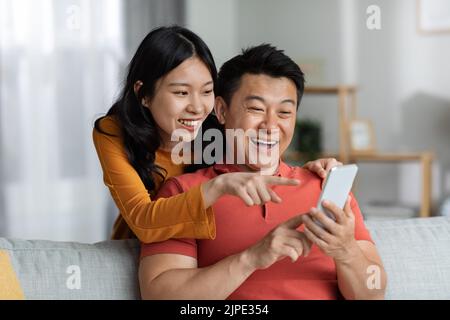 Happy japanese couple using smartphone together at home Stock Photo