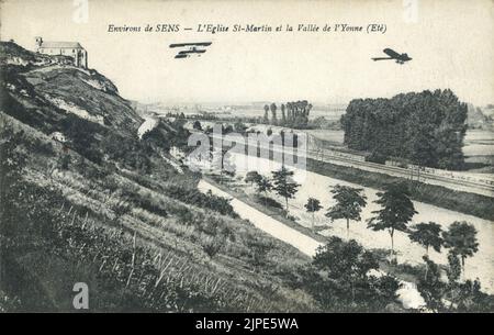 Vintage black and white postcard from the early twentieth century featuring a photograph of early aerial show with monoplane and biplane flying overhead - aviation history circa 1910 - 1915 Stock Photo