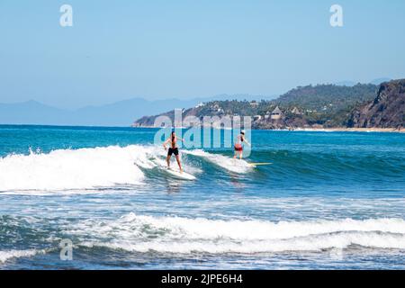 Two guys surfing on a wave on a beach in Sayulita, Mexico Stock Photo