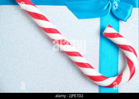 Christmas gift box with blue bow and a red and white candy shape of cane Stock Photo
