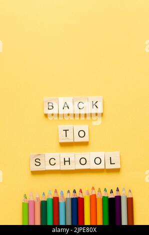 Back to class. Coloured pencils and letters BACK TO SCHOOL on yellow background. Copy space. vertical photo. Stock Photo