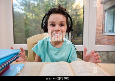 Close-up schoolboy in headphones, doing literature homework. Open to new knowledge in new semester of the academic year. Stock Photo