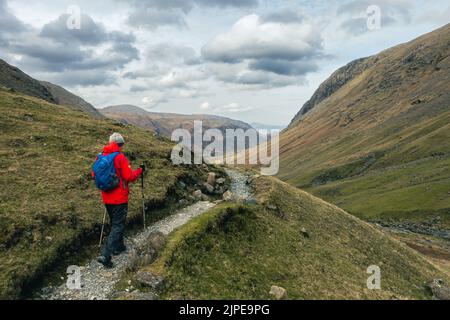 Hill walker on the path past Grains Gill from Great End towards Seathwaite, Lake District National Park, Cumbria, UK landscapes Stock Photo