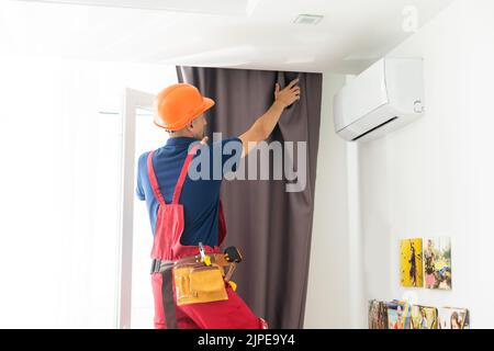 man screwing window curtain rod support on the wall Stock Photo
