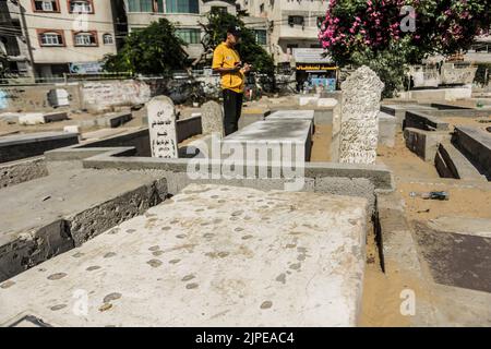 Gaza, Palestine. 17th Aug, 2022. Relative of five Palestinian children killed during the recent fighting between Israel and Gaza stands near their graves, in Jabalia in the northern Gaza Strip. Israel has admitted to killing five Palestinian children in an air raid on the Fallujah cemetery in the town of Jabalia, in the northern Gaza Strip, on August 7th, after initially claiming they were killed as a result of a missile fired by Islamic Jihad, Israel's Haaretz newspaper reported. (Photo by Mahmoud Issa/SOPA Images/Sipa USA) Credit: Sipa USA/Alamy Live News Stock Photo