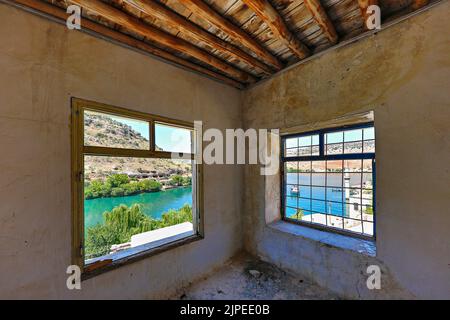 Euphrates river and the minaret that remained under the water of Birecik Dam through the windows of an abandoned house in Halfeti, Turkey Stock Photo
