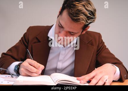 A teacher reviewing papers in the classroom. Business man dressed in cafe suit signing important papers. Man working in his office. A sales executive Stock Photo