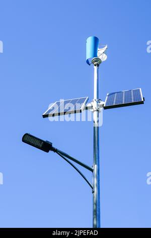 Pole with innovative LED street light powered by solar cells and small vertical wind generator, blue sky background Stock Photo