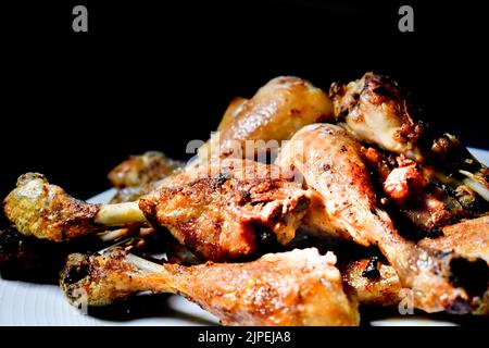 A pile of perfectly cooked  juicy and crispy oven roast chicken drum sticks on a white plate Stock Photo