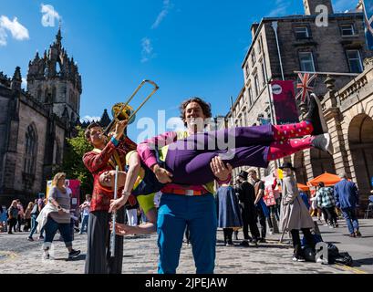 Royal Mile, Edinburgh, Scotland, UK, 17th August 2022. Performers on Royal Mile in the sunshine. Pictured: actors playing musical instruments including a flute and trombone from a Fringe show called Fruit Flies Like a Banana children's entertainment. Credit: Sally Anderson/Alamy Live News Stock Photo