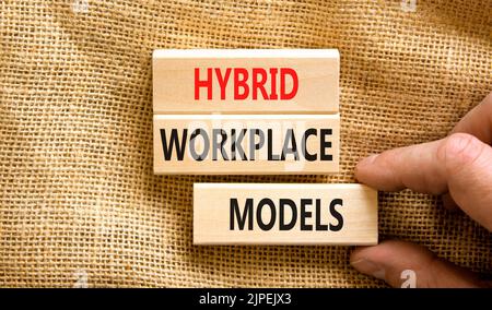 Hybrid workplace models symbol. Concept words Hybrid workplace models on wooden blocks. Businessman hand. Beautiful canvas background. Business hybrid Stock Photo