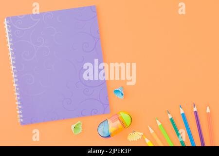 Spiral lilac notebook with colored pencils. Stock Photo