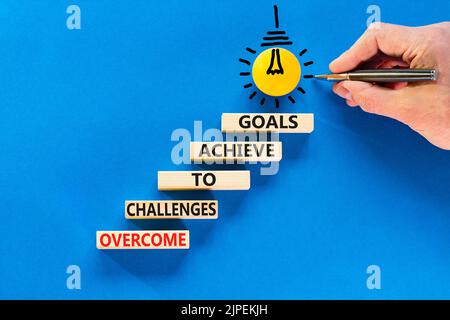 Overcome challenges to achieve goals symbol. Concept words Overcome challenges to achieve goals on wooden blocks on a beautiful blue background. Busin Stock Photo