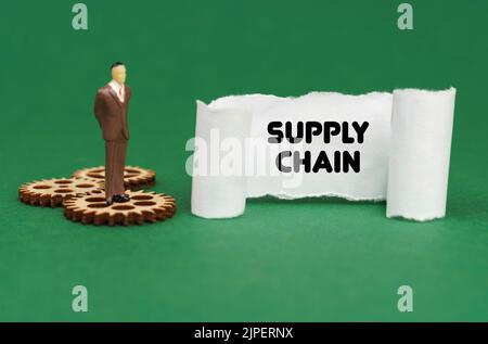 Business concept. The figure of a man stands on the gears and reads the inscription - SUPPLY CHAIN on paper Stock Photo