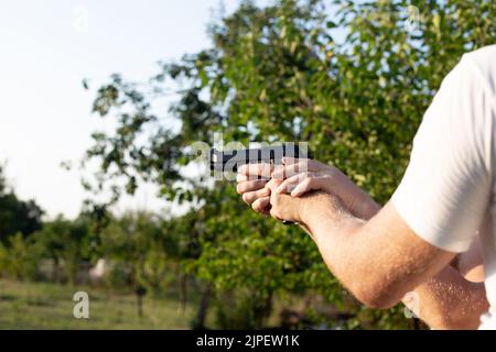 The man supports the hands of another man in which the gun. Pistol shooting training. Recreation and hobby. Stock Photo