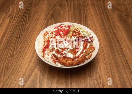 Breaded chicken fillet with sauces, cooked basmati rice and salad with lettuce and tomato slices Stock Photo