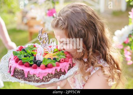 girl take bite of off piece of congratulatory cake. Birthday and congratulations concept. Stock Photo