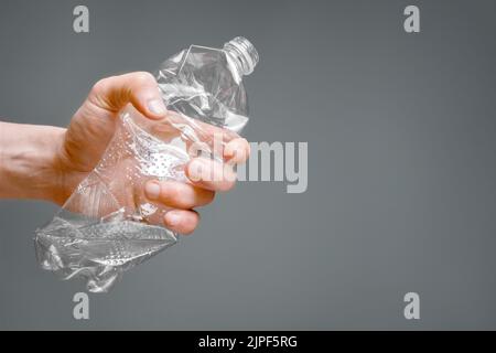 Crumpled bottle pet plastic resize or zero waste plastic hand recycling garbage crush. Raised hands holding crumpled plastic bottle hand squeeze Stock Photo