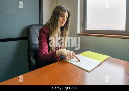 Young blonde business woman sitting in her office checking notes Stock Photo