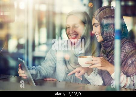 Technology connects online and in real life. two women using a digital tablet together in a cafe. Stock Photo