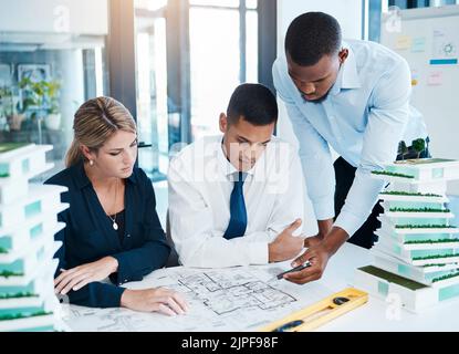 Designers and architects working on construction plan, planning with blueprint paperwork and talking in a meeting in office at work. Creative Stock Photo