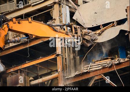 Hydraulic scissors on rigging demolish industrial building Stock Photo