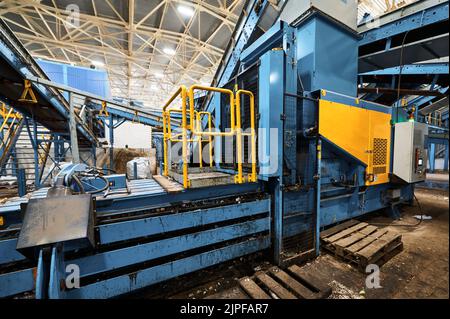 Machine for compacting household waste. Compaction of garbage into briquettes and bales. Stock Photo