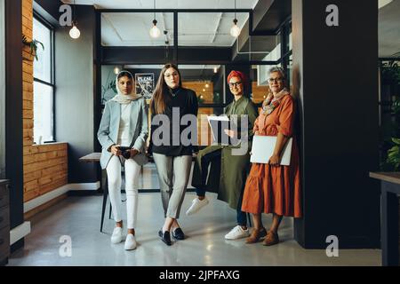 Group of creative designers looking at the camera in an office boardroom. Multicultural businesswomen working as a team in an inclusive workplace. Div Stock Photo