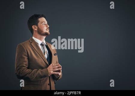 Hes a visionary leader. Studio shot of handsome young businessman looking thoughtful against a dark background. Stock Photo